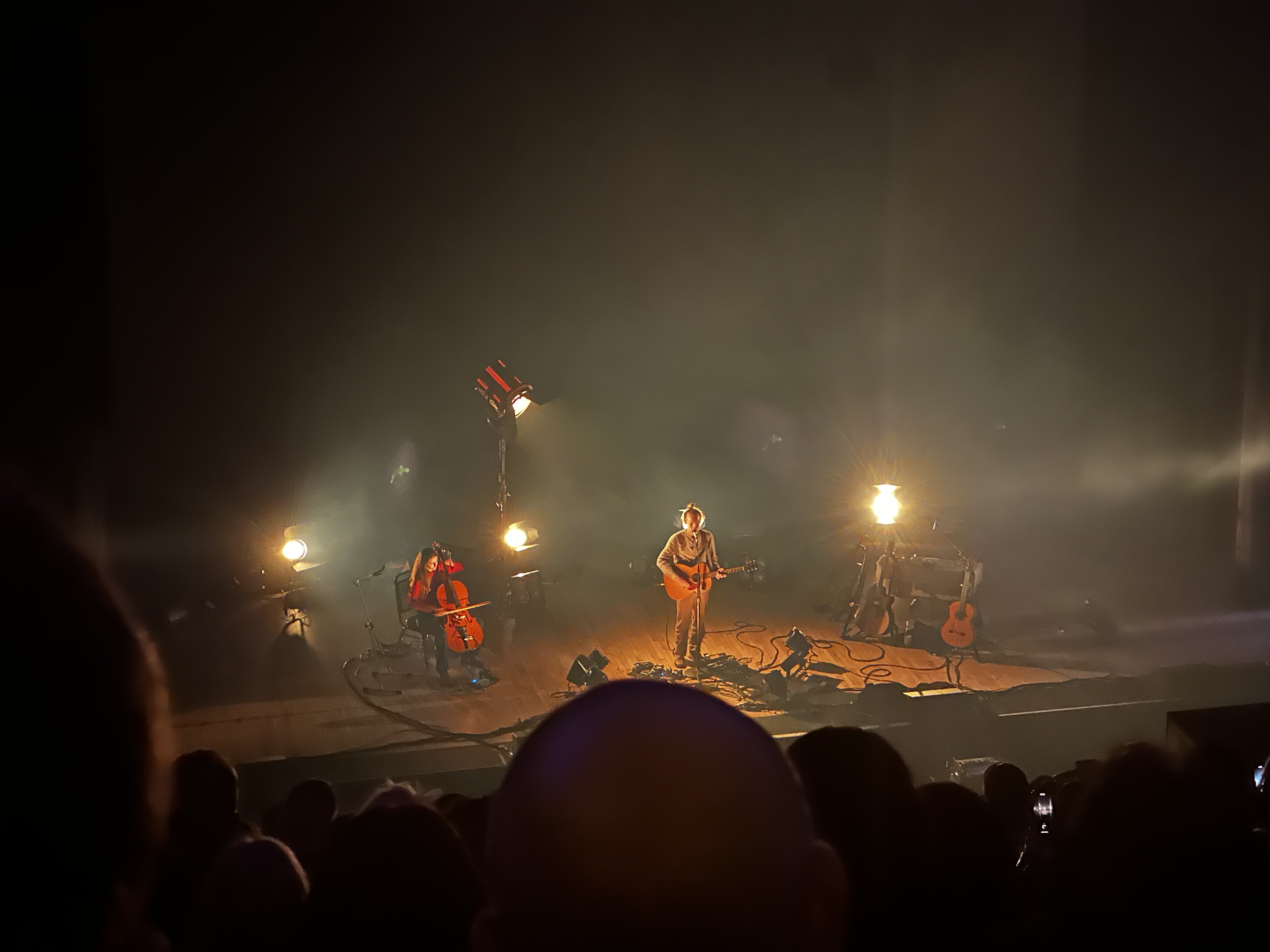 Intimate acoustic concert with guitarist and cellist, warm amber stage lighting