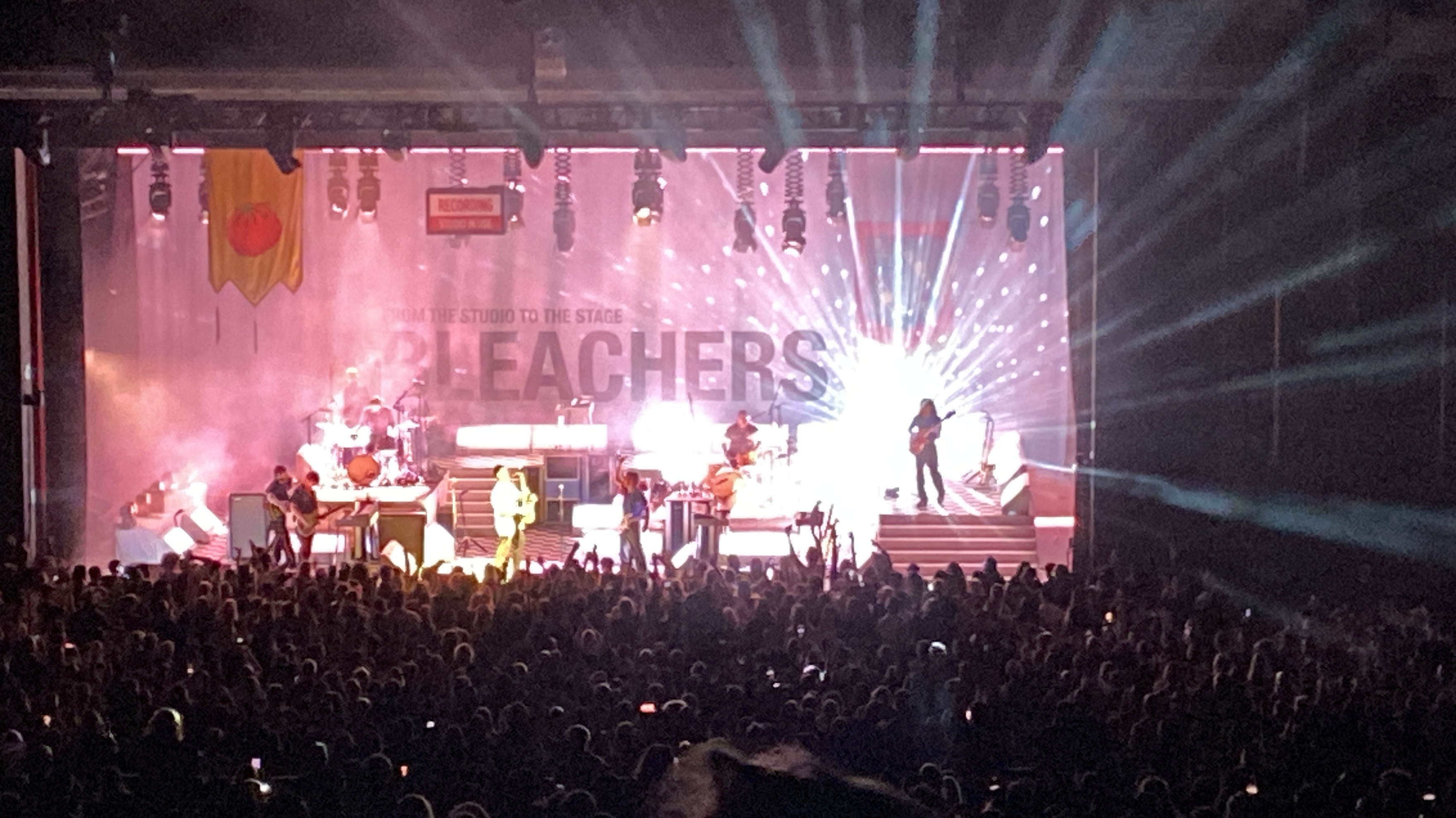Bleachers indoor concert with dramatic light beams