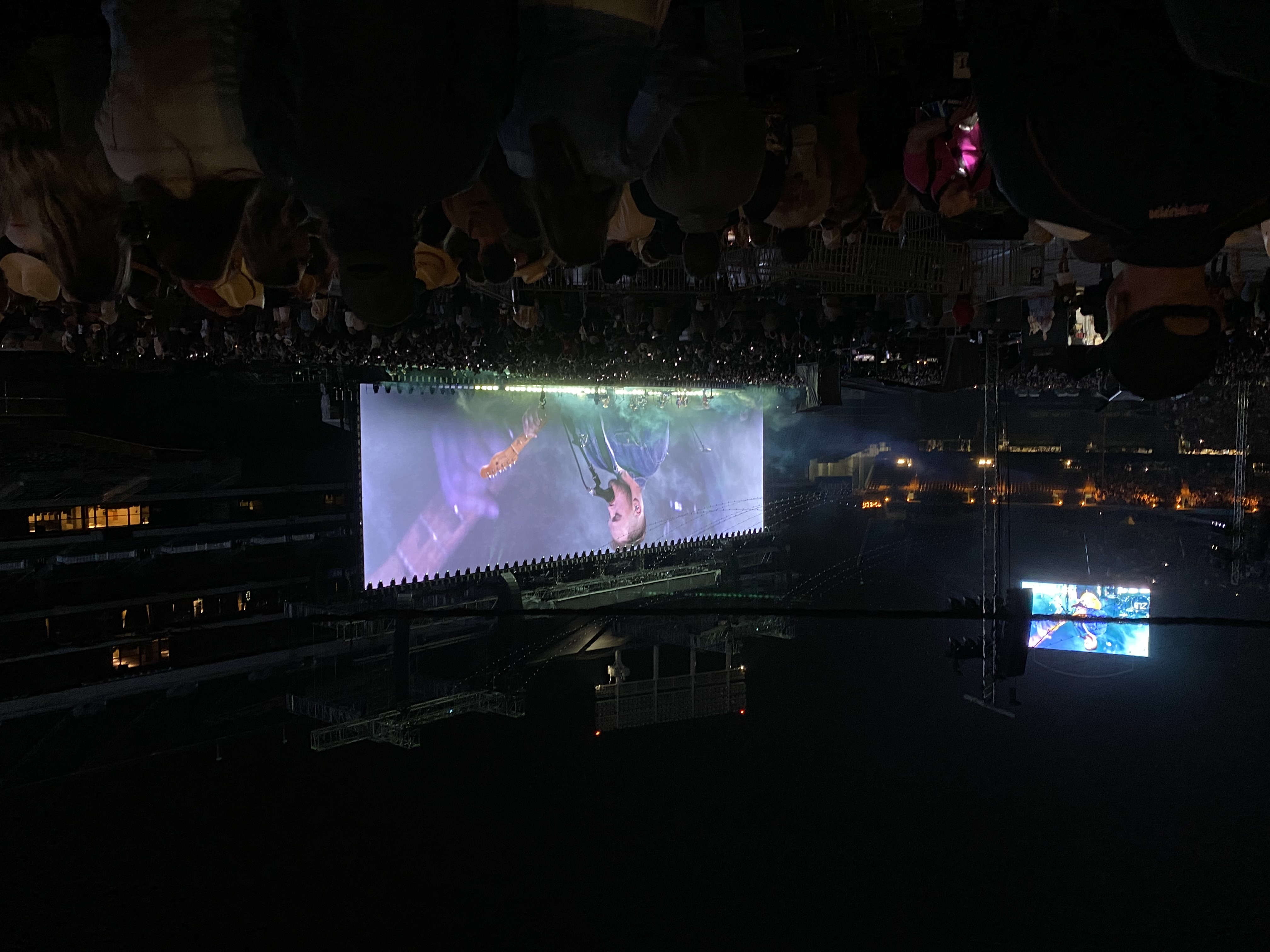Stadium concert at night with guitarist on large video screens