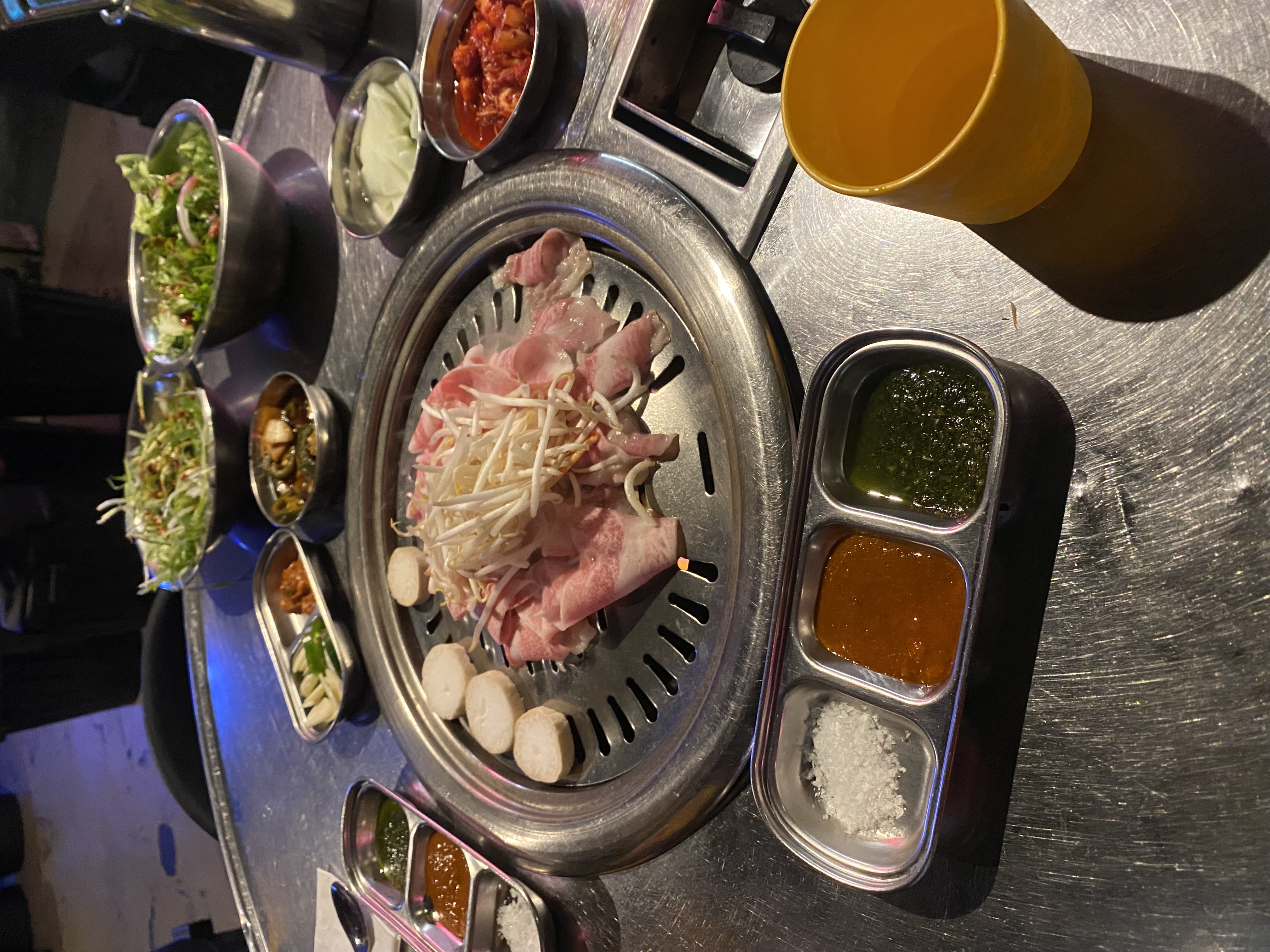Korean BBQ with meat on grill and banchan