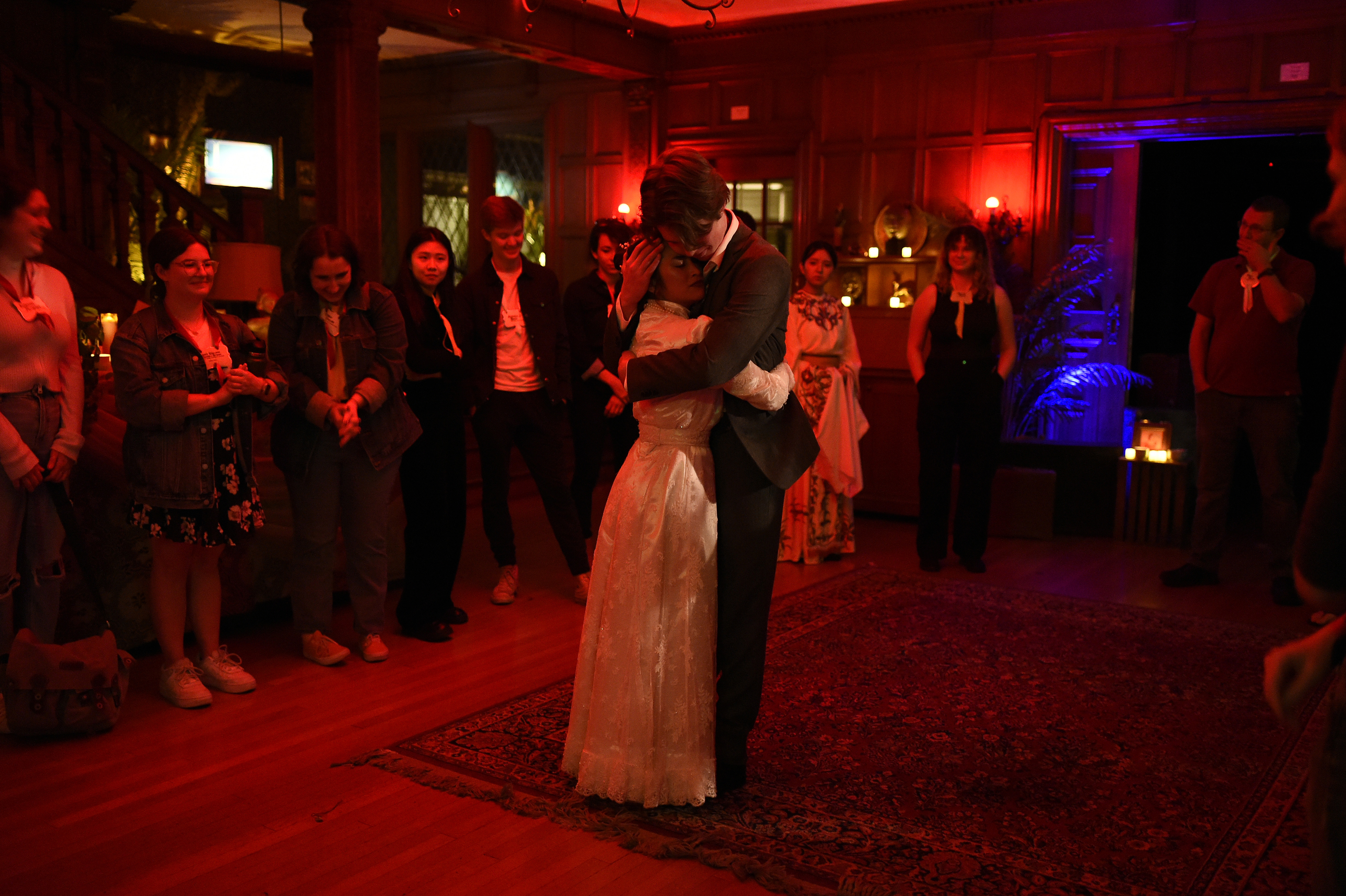 Ghosts of USC - Couple embracing in deep red lighting with audience