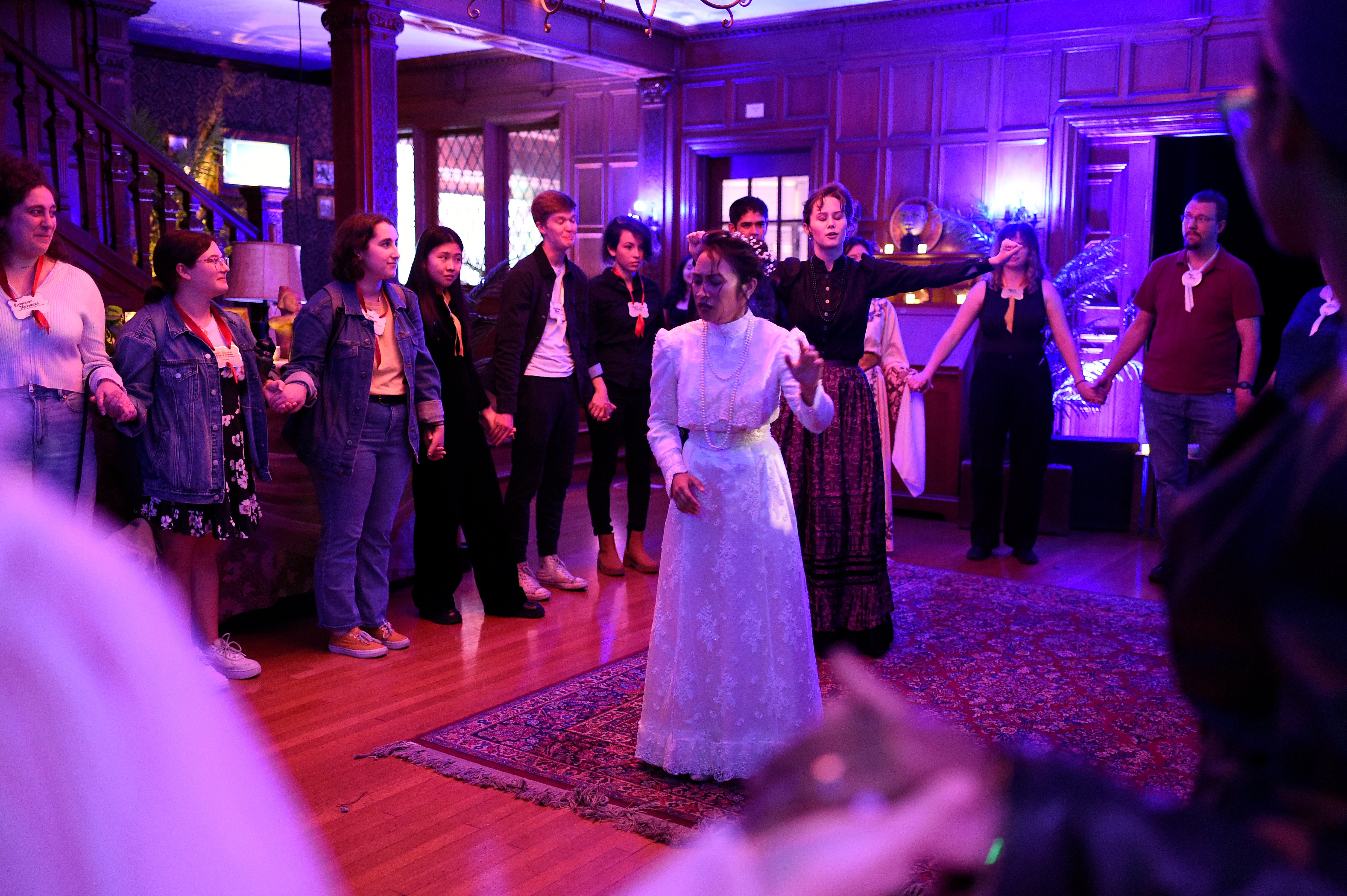 Ghosts of USC - Woman in white leading seance with audience in circle