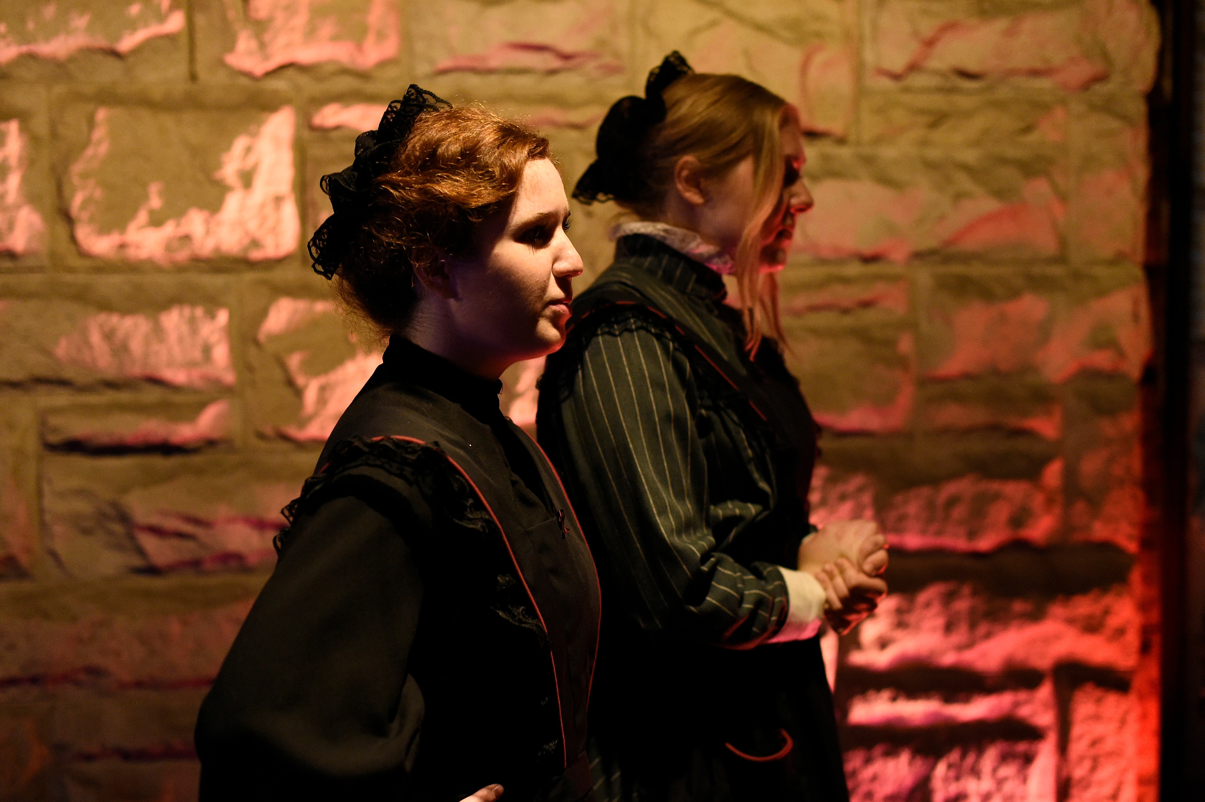 Ghosts of USC - Two women in Victorian black dresses against stone wall