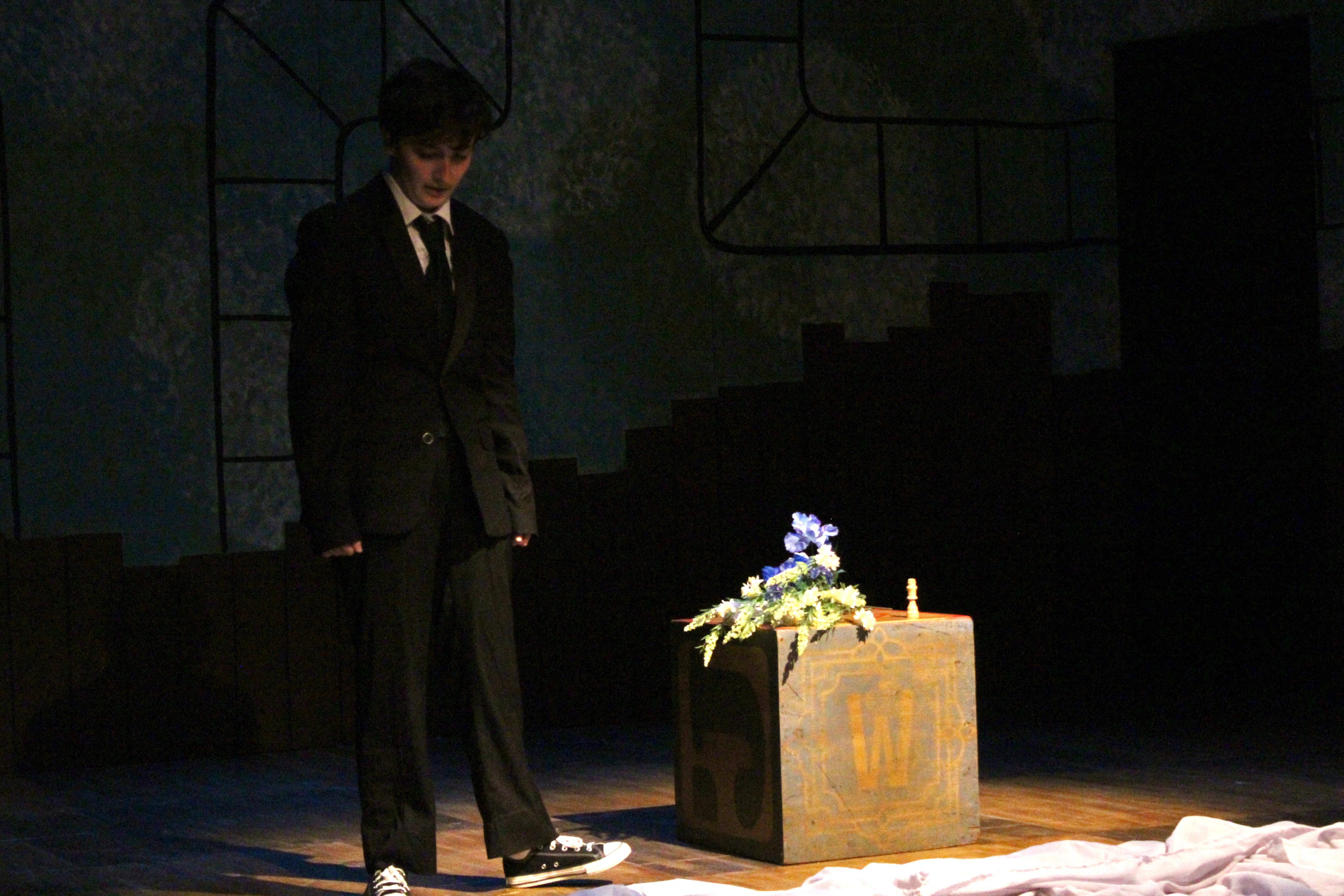 Falsettos - Funeral scene with flowers and cityscape backdrop