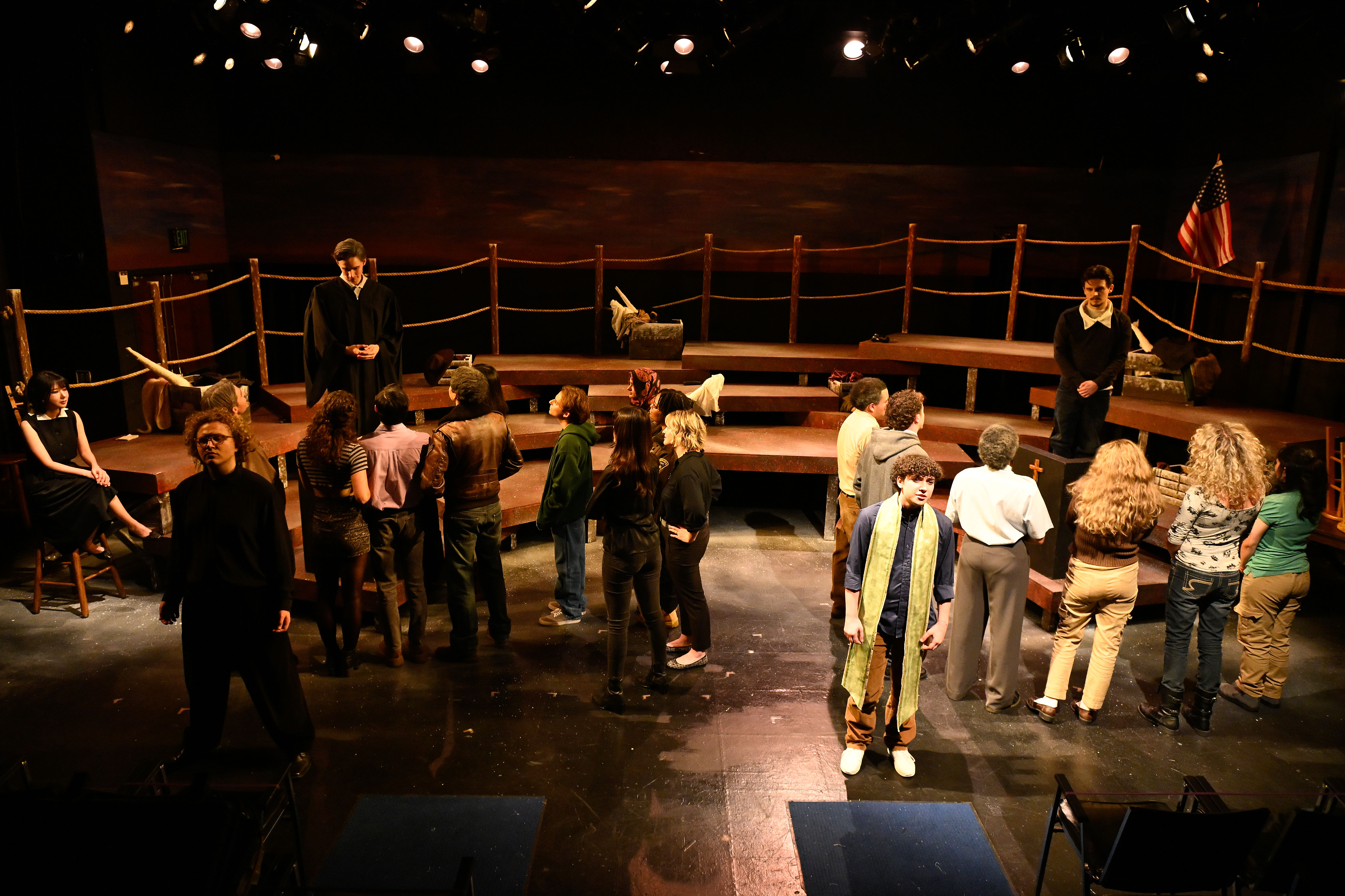 The Laramie Project - Full cast gathered around platforms with priest in yellow scarf
