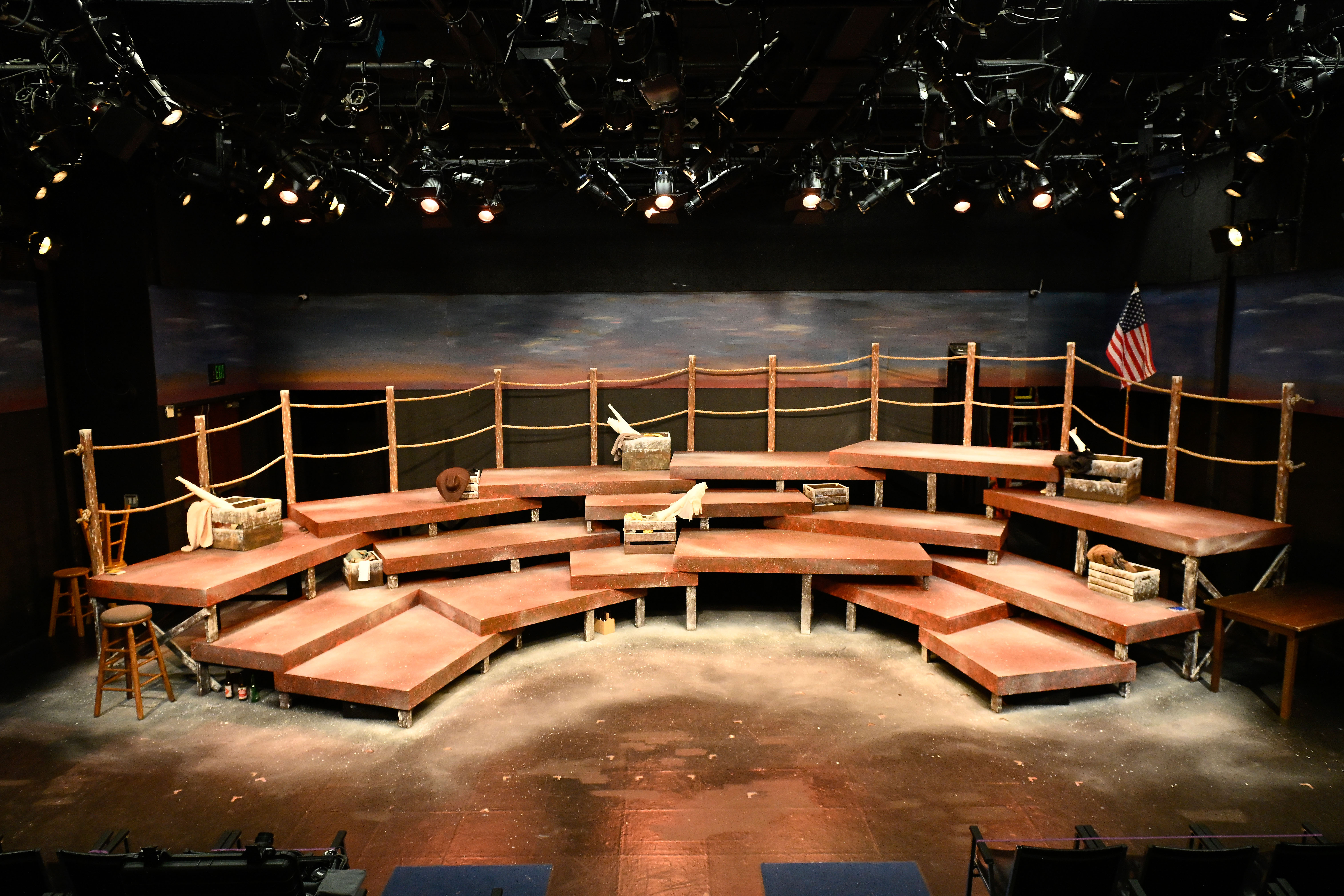 The Laramie Project - Full set with tiered rust platforms, wooden fence, and painted sky cyclorama