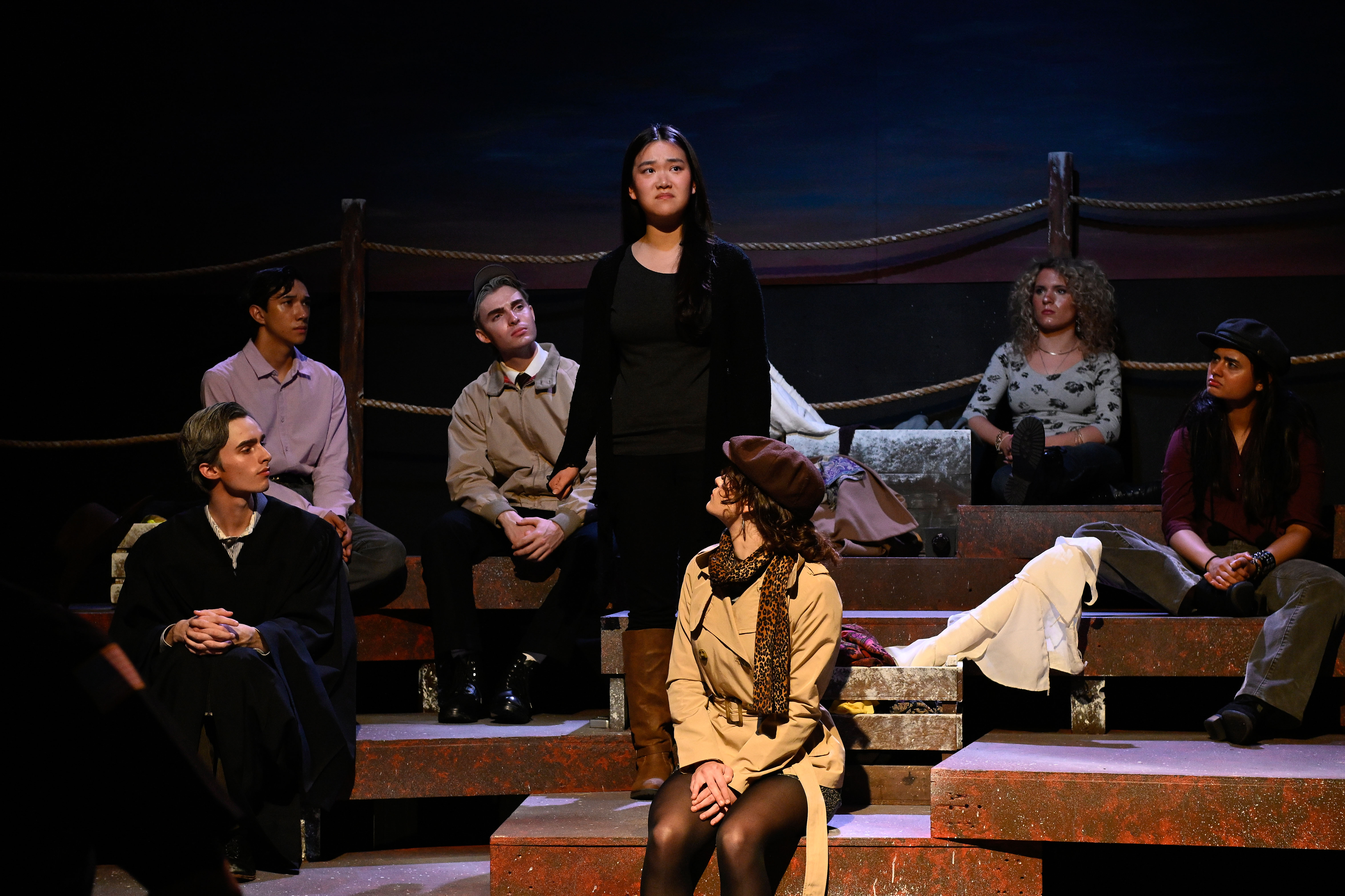 The Laramie Project - Woman standing center with ensemble seated on platforms