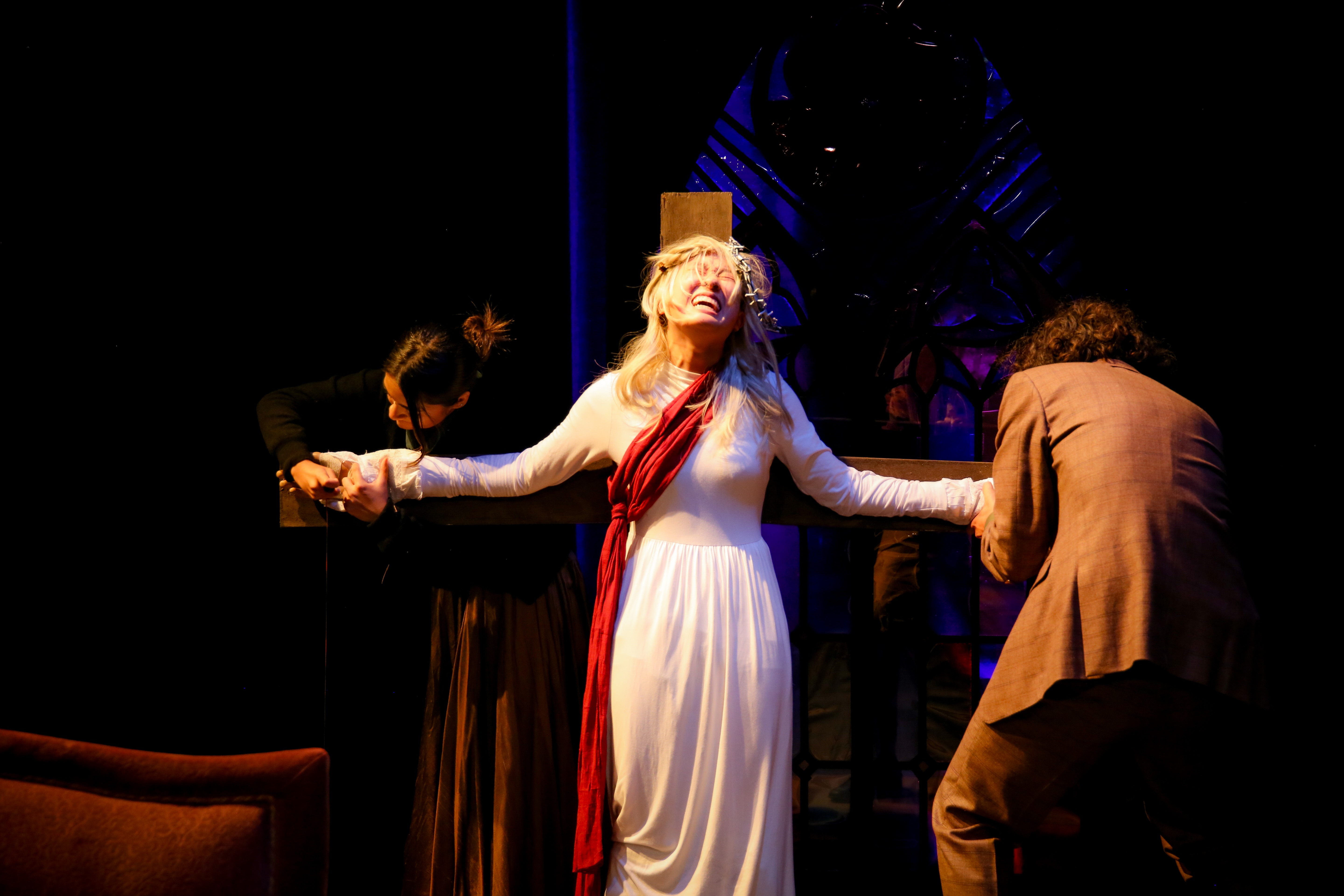 The Pillowman - Woman on cross with two figures, stained glass behind