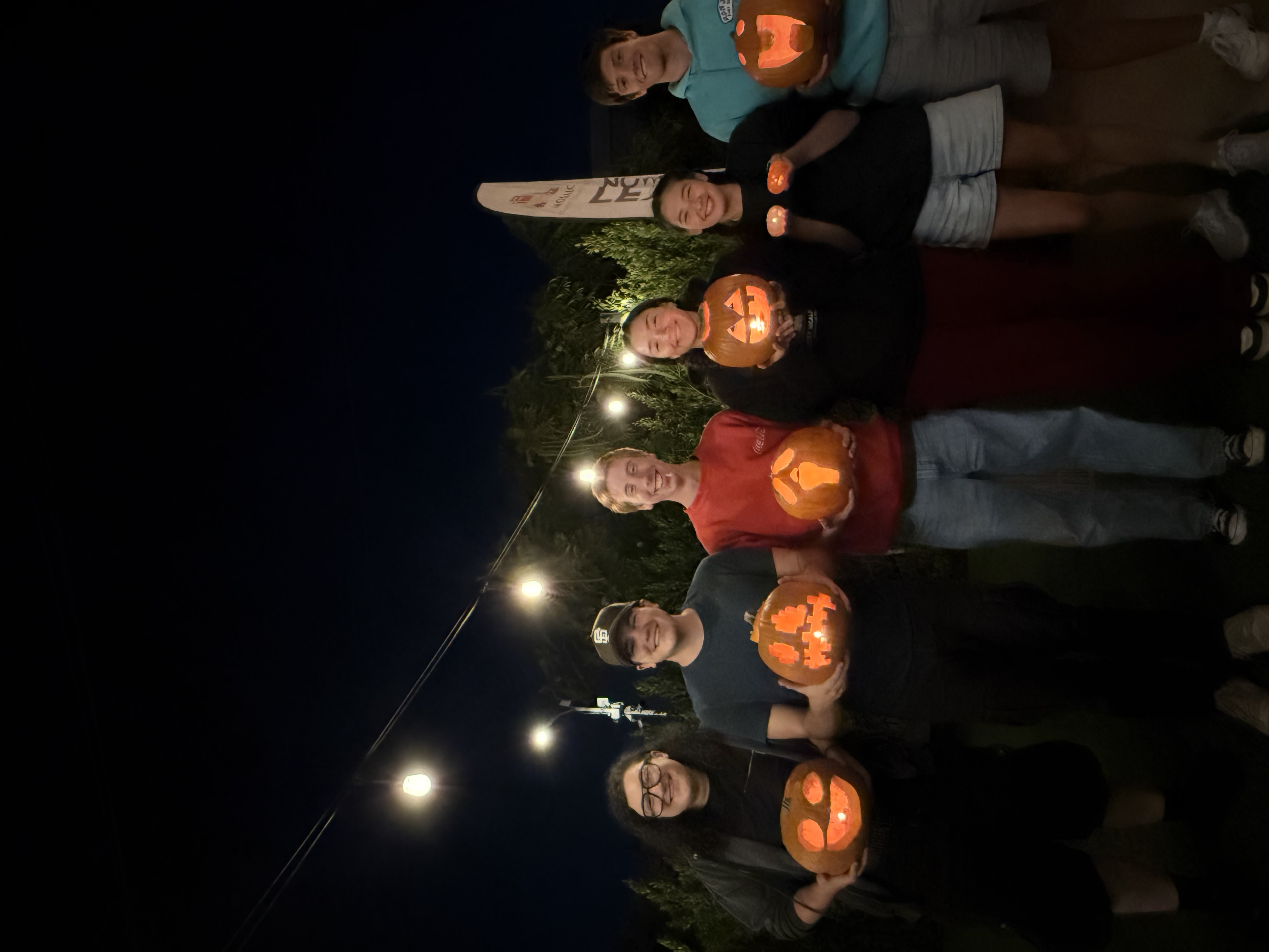Friends with carved jack-o-lanterns at night