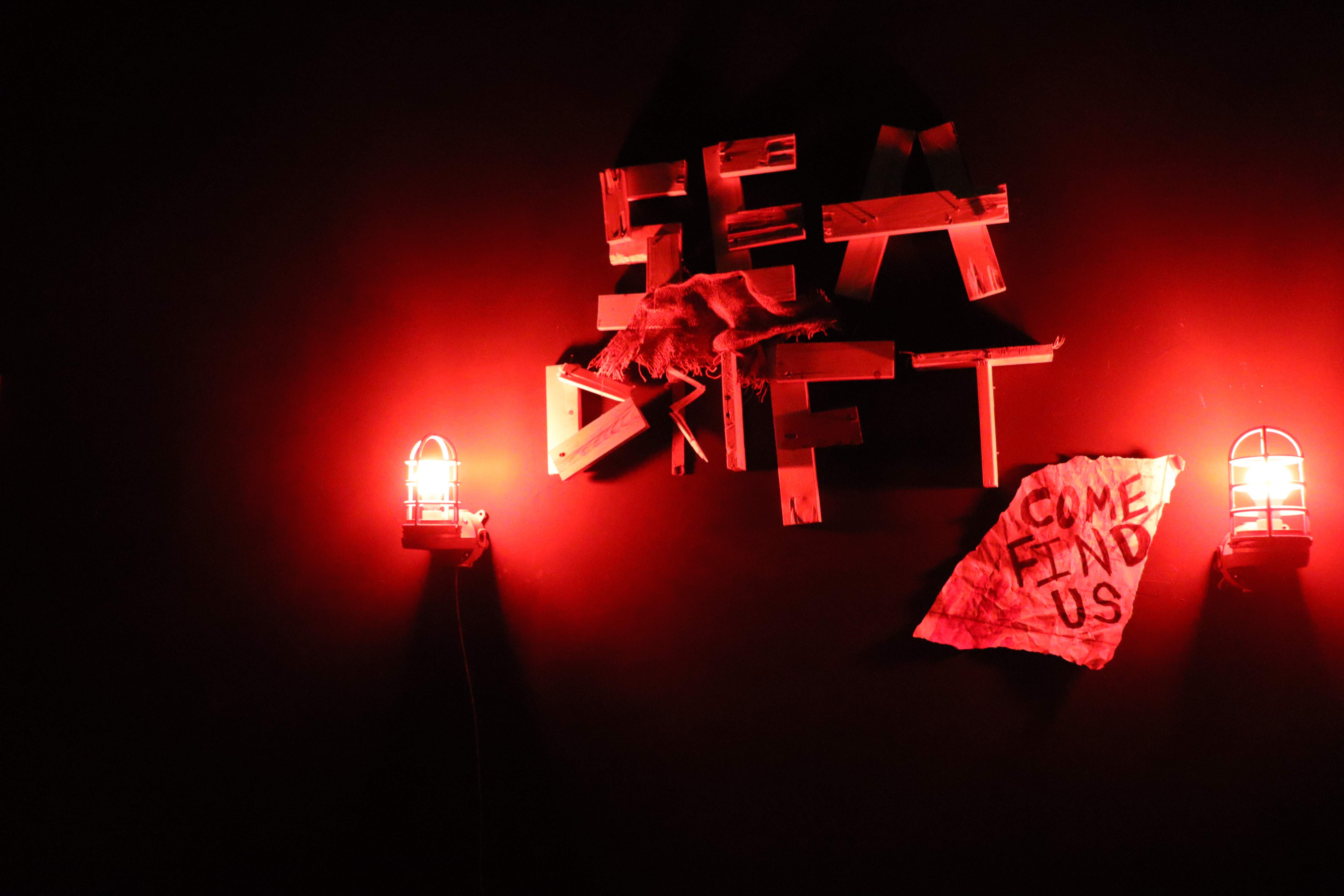 Sea Drift - Red-lit sculptural title sign with Come Find Us paper