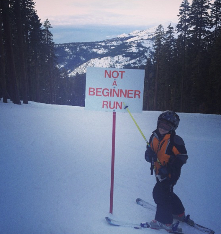 Young skier next to Not A Beginner Run sign