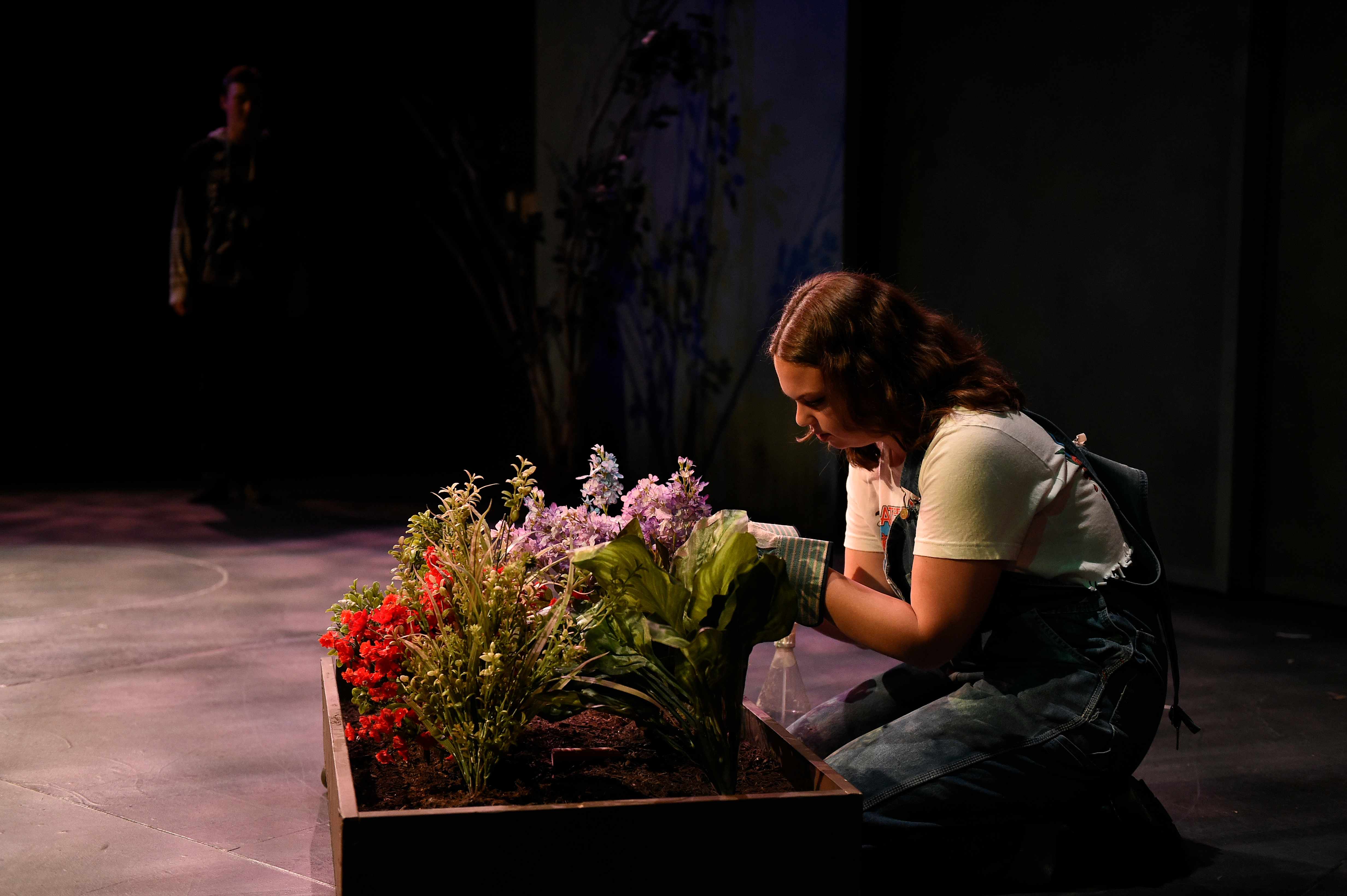 Somewhere Someone - Woman kneeling by flower box with purple lighting