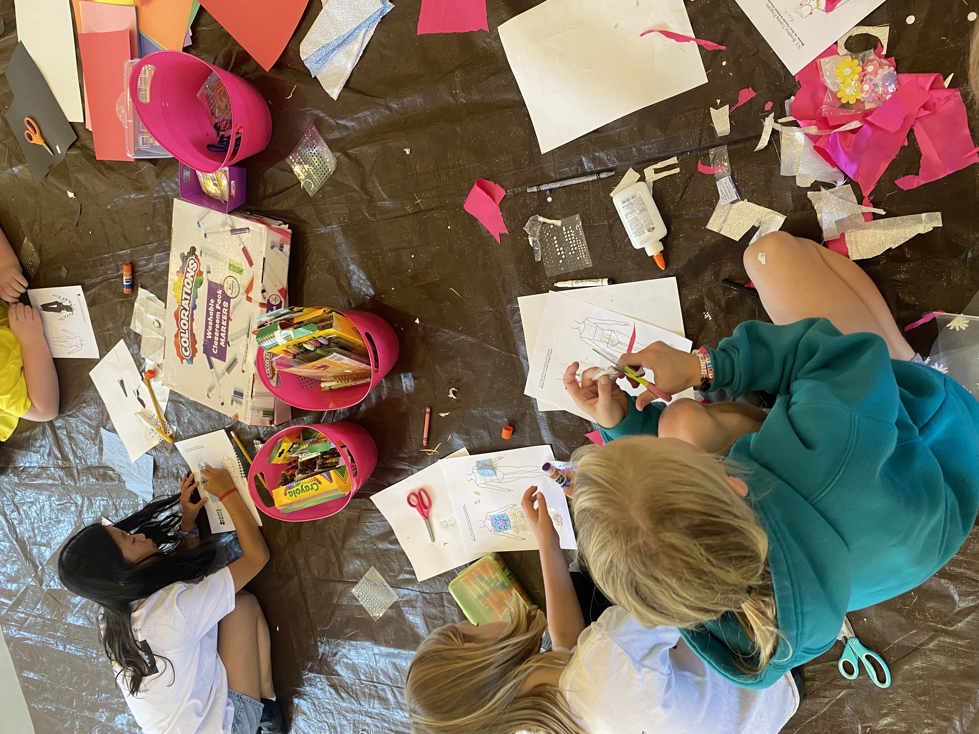 Teaching - Students working on costume design templates with art supplies on floor