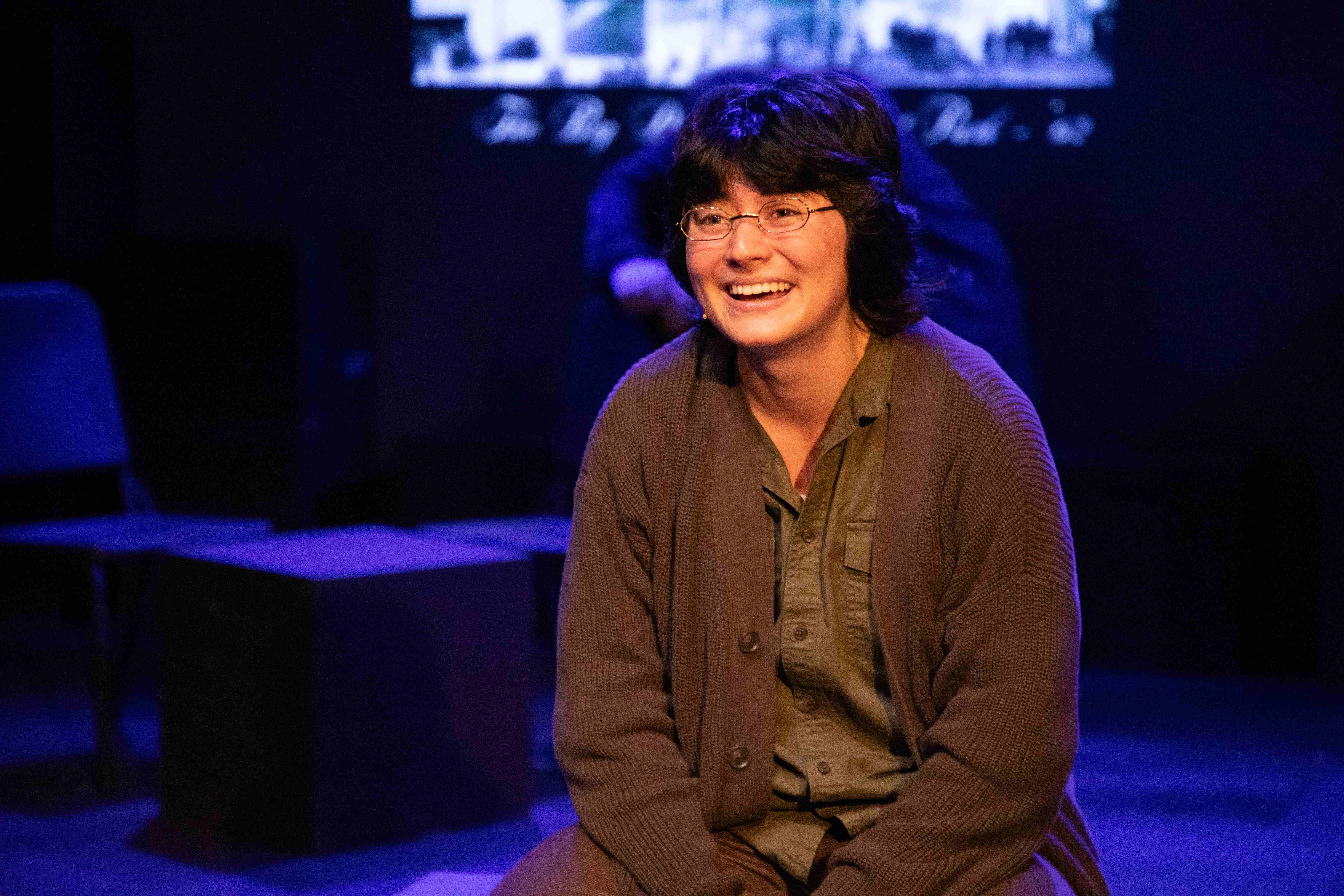 Working - Woman laughing in brown cardigan with blue lighting