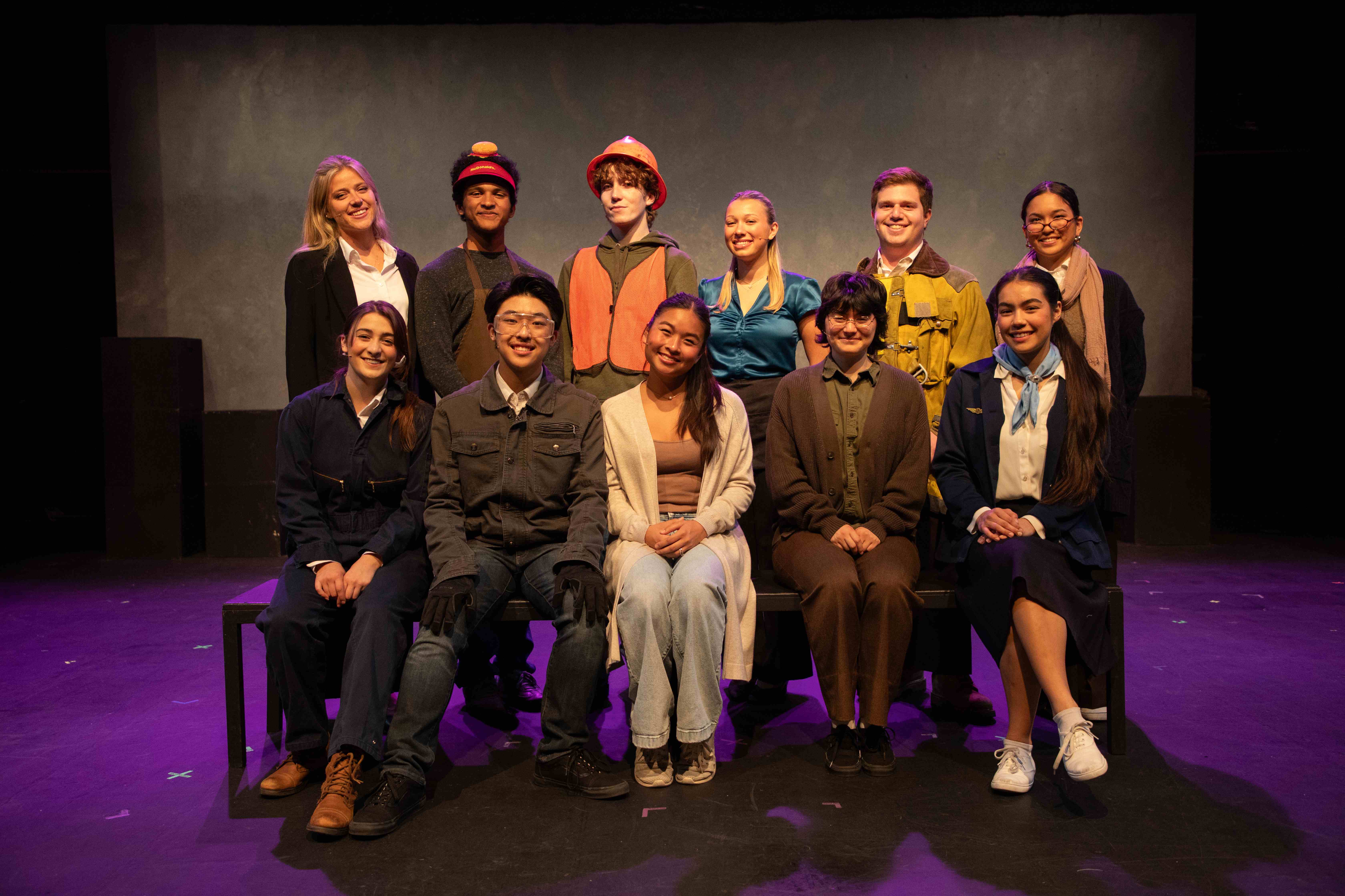 Working - Full cast photo in worker costumes with purple lighting