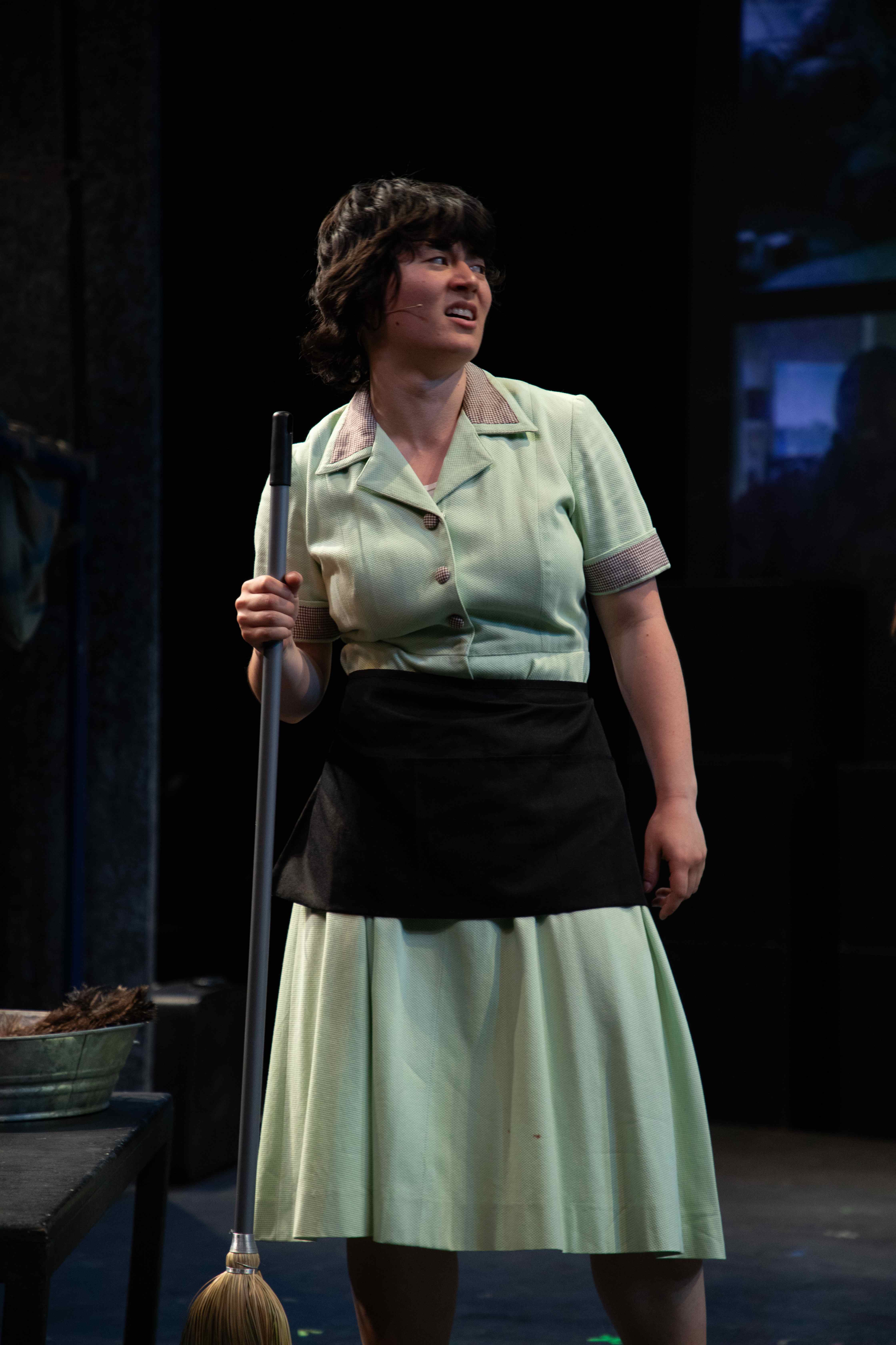 Working - Housekeeper in mint green uniform with broom