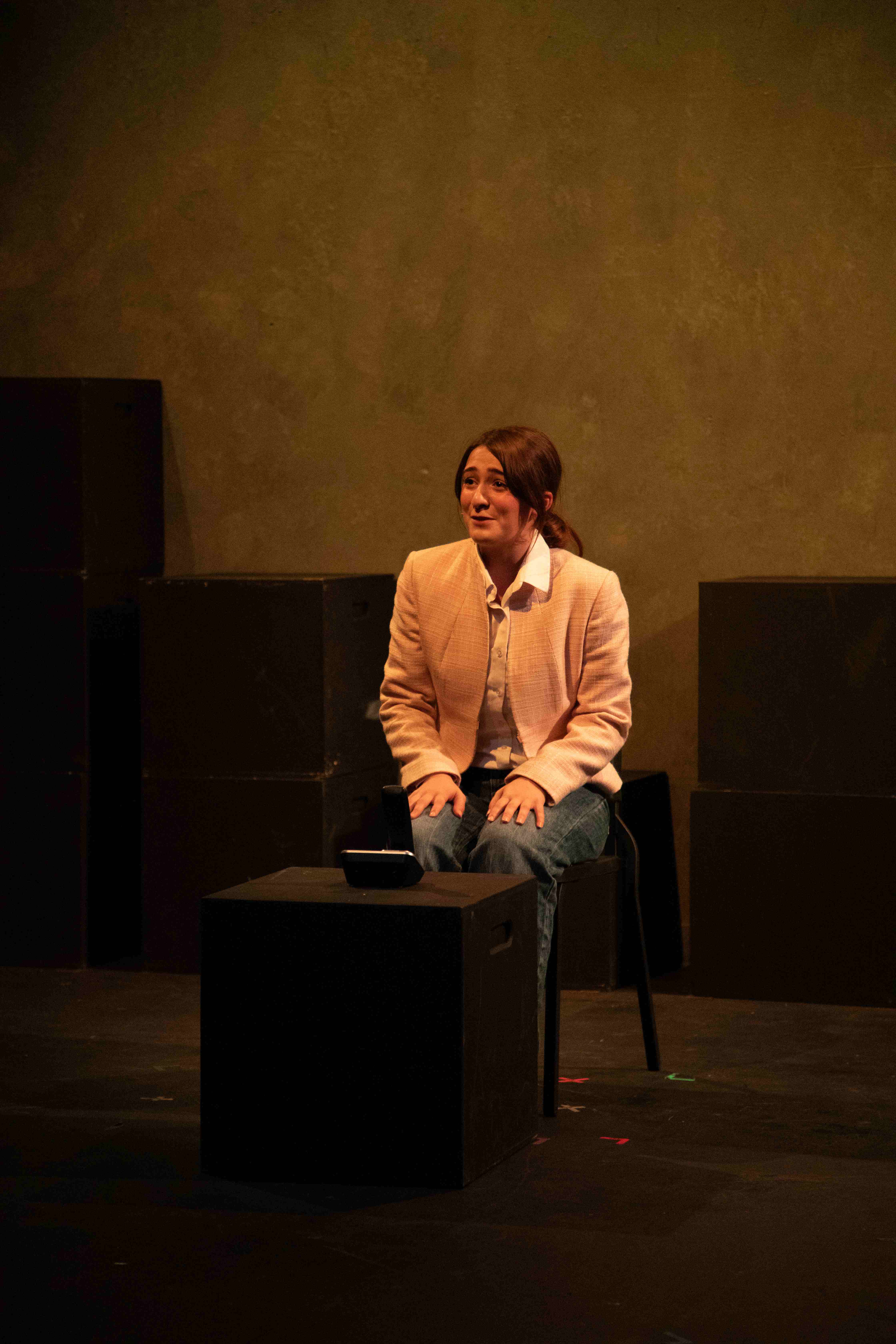 Working - Woman in pink blazer seated on stage
